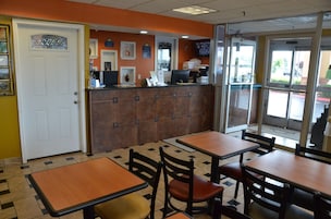 A restaurant interior with a counter, tables, and chairs.