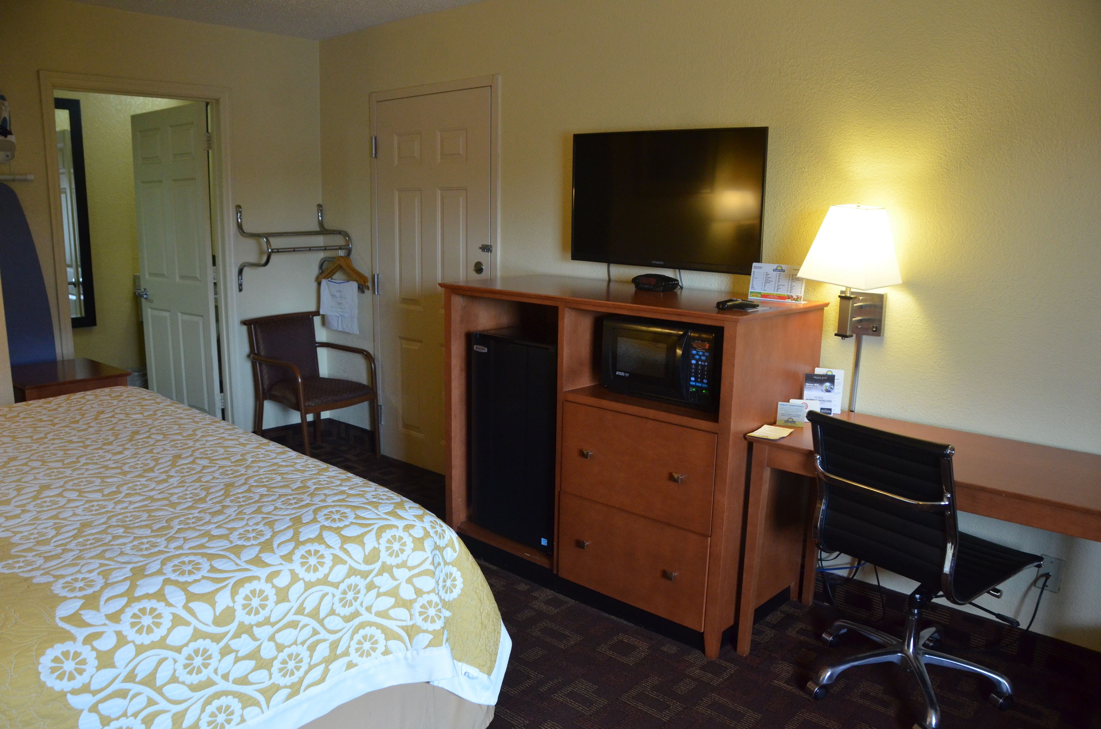 Ein Hotelzimmer mit Bett, Schreibtisch, Fernseher, Stuhl und Lampe.