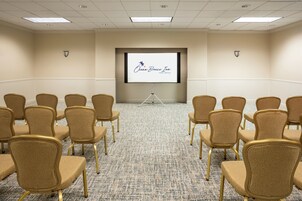 A conference room with rows of chairs facing a projection screen displaying 'Ocean Breeze Inn Vero Beach FL'.