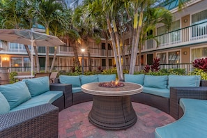 Relax in a serene outdoor seating area surrounded by lush greenery and comfortable wicker furniture.