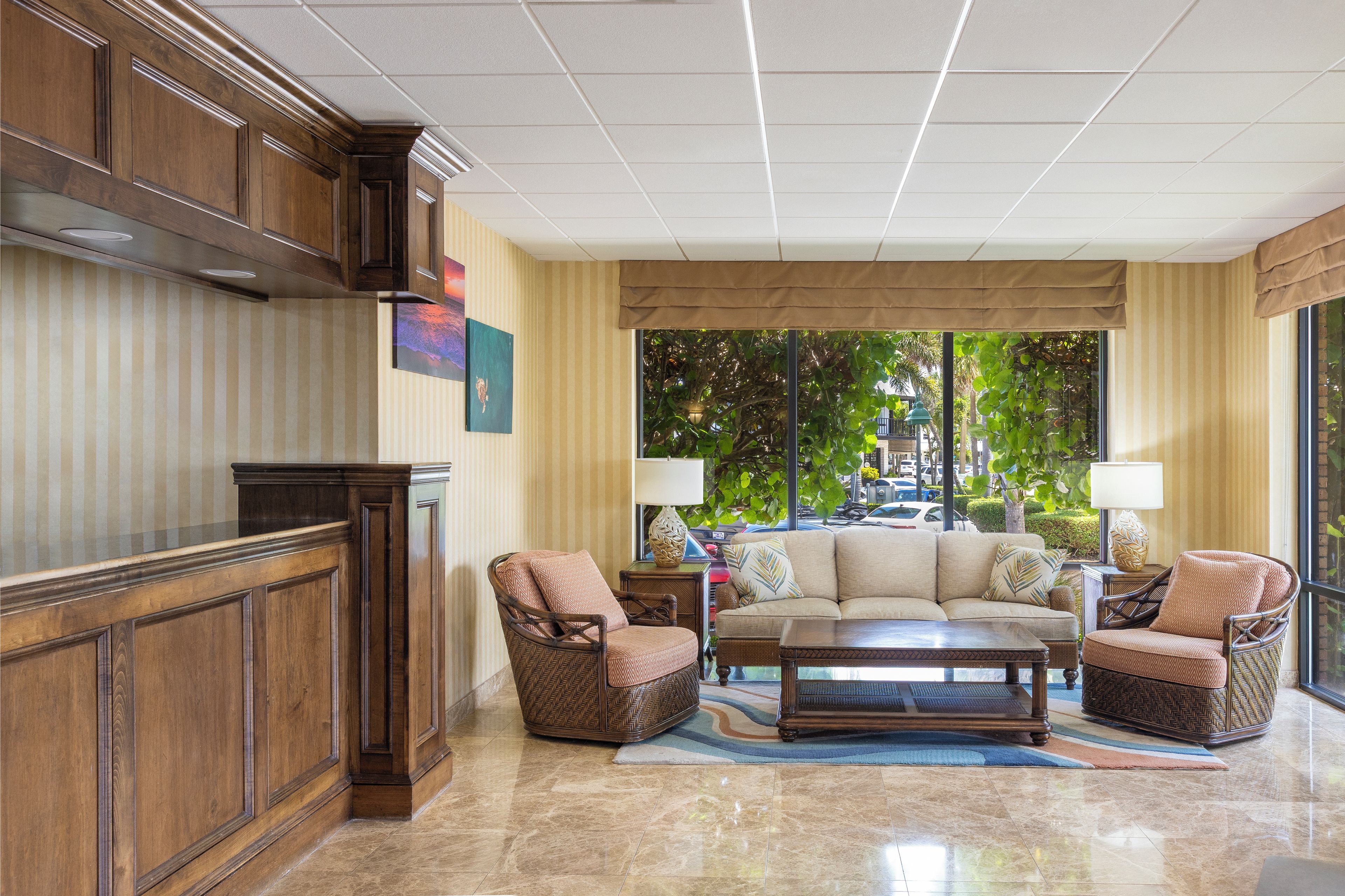 A spacious living area with a large window, a sofa, two armchairs, a coffee table, and a wooden cabinet.