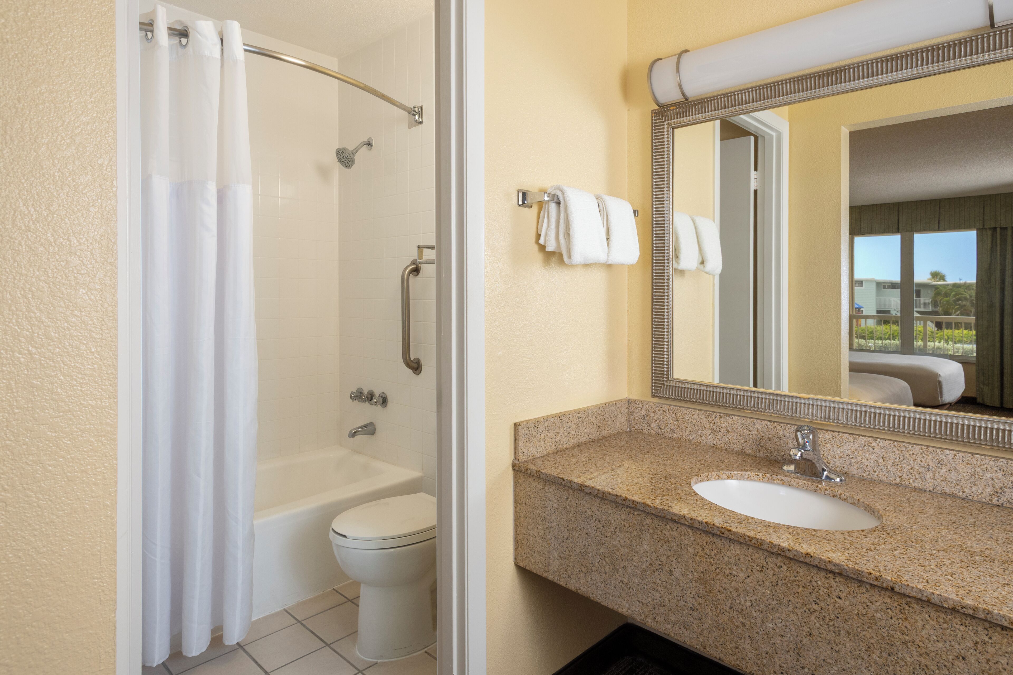 A bathroom with a shower, toilet, sink, and a mirror.
