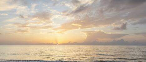 A beach with a sunset over the ocean.