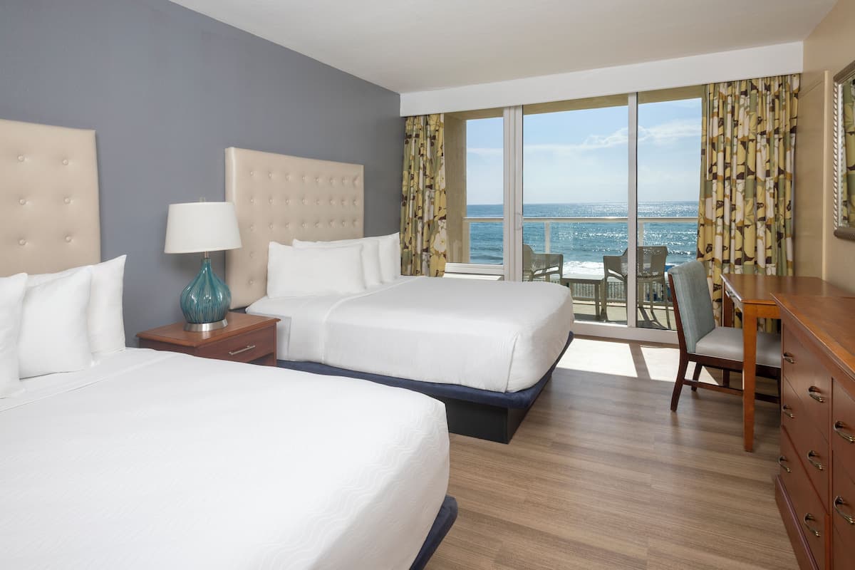 A hotel room with two beds, a desk, and a chair.