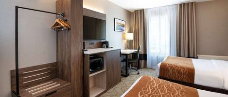 Habitación de hotel con cama, escritorio, televisor, microondas y perchero.