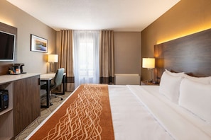 A hotel room with a bed, a desk, a chair, a television, and a window with curtains. - Comfort Inn Lakeshore (North Bay)