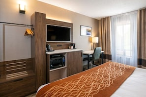 A hotel room with a bed, a desk, a television, a microwave, and a coffee maker. - Comfort Inn Lakeshore (North Bay)
