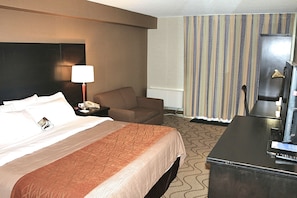 A hotel room with a bed, a desk, a chair, a lamp, and a television. - Comfort Inn Lakeshore (North Bay)