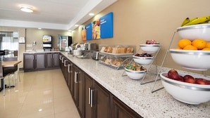 A breakfast buffet area with various food items and a coffee station.