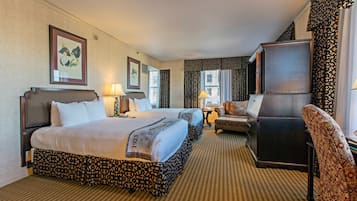 A hotel room with two beds, a desk, a chair, and a large mirror.