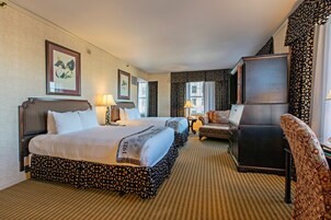 Quarto de hotel com duas camas, uma escrivaninha, uma cadeira e um espelho grande.