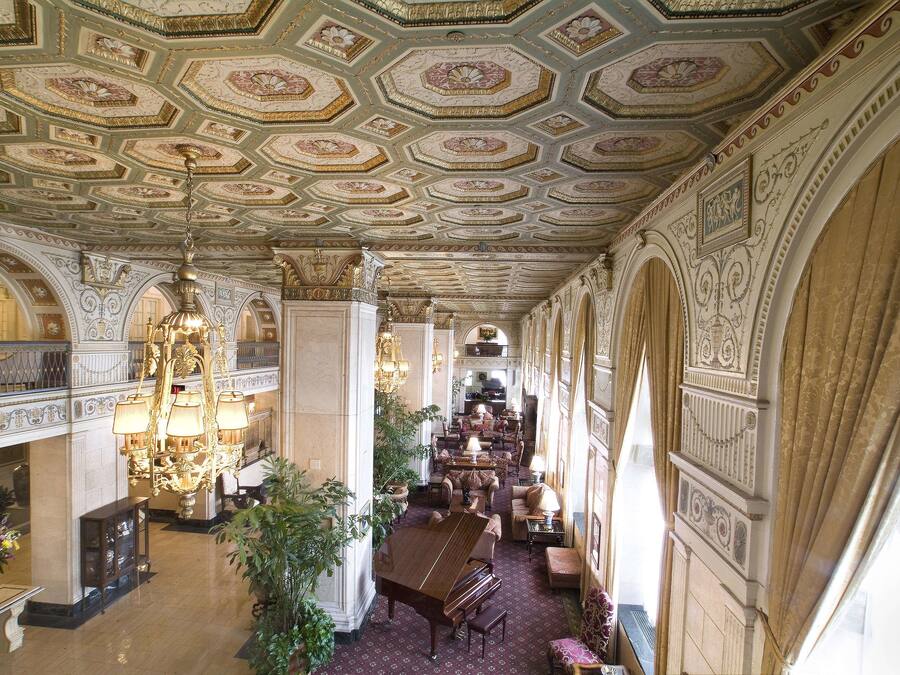 A grand lobby with ornate ceiling, chandeliers, and a central seating area.