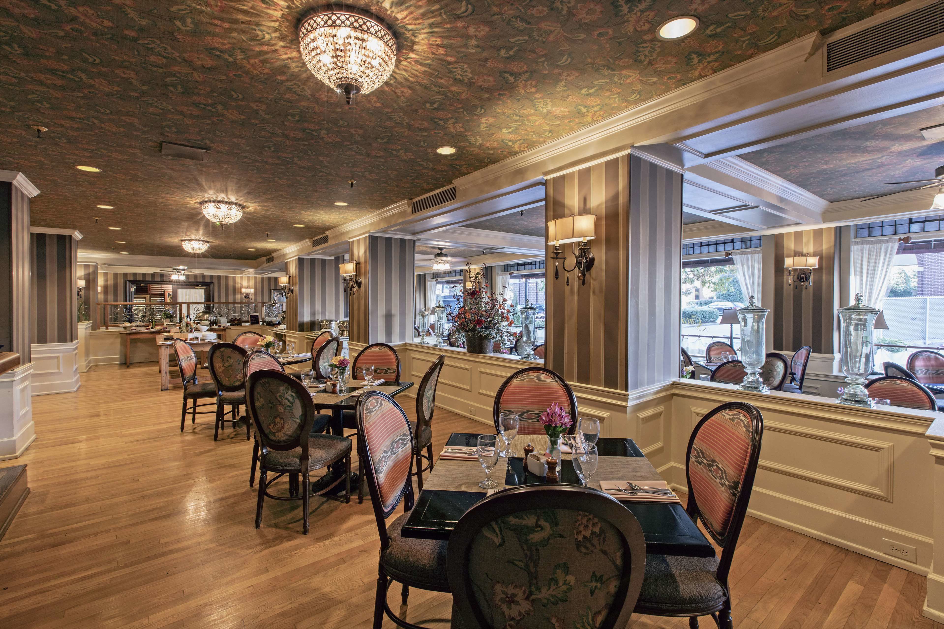 A dining area with wooden floors, upholstered chairs, and a chandelier.