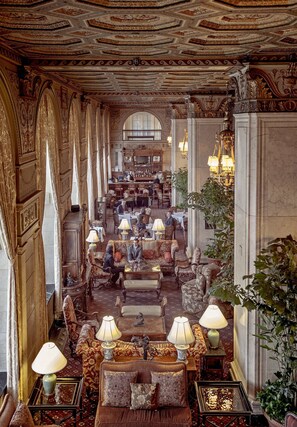 A grand lobby with ornate columns, plush seating, and a chandelier.