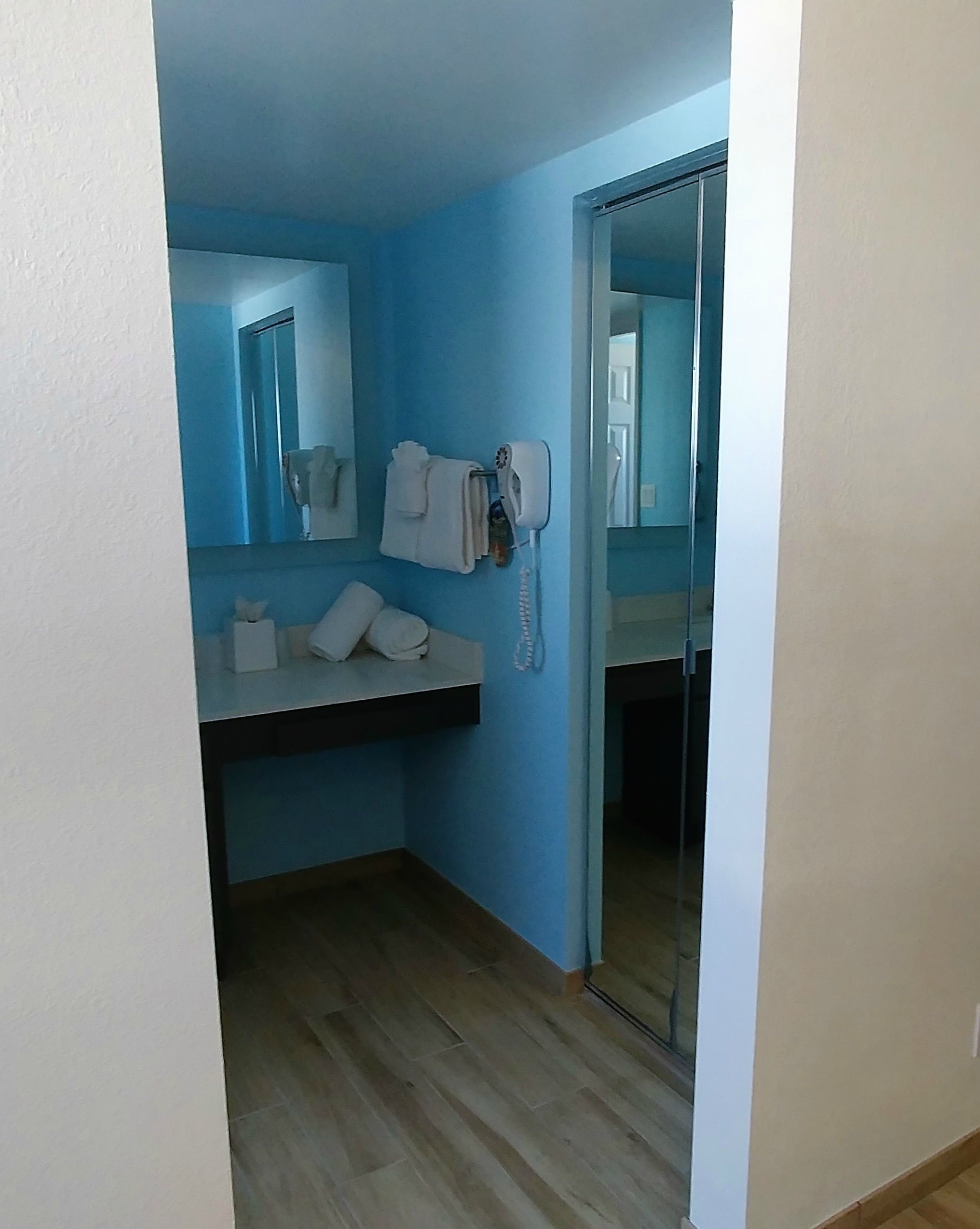A bathroom with a blue wall, a white sink, a hairdryer, and a mirror.