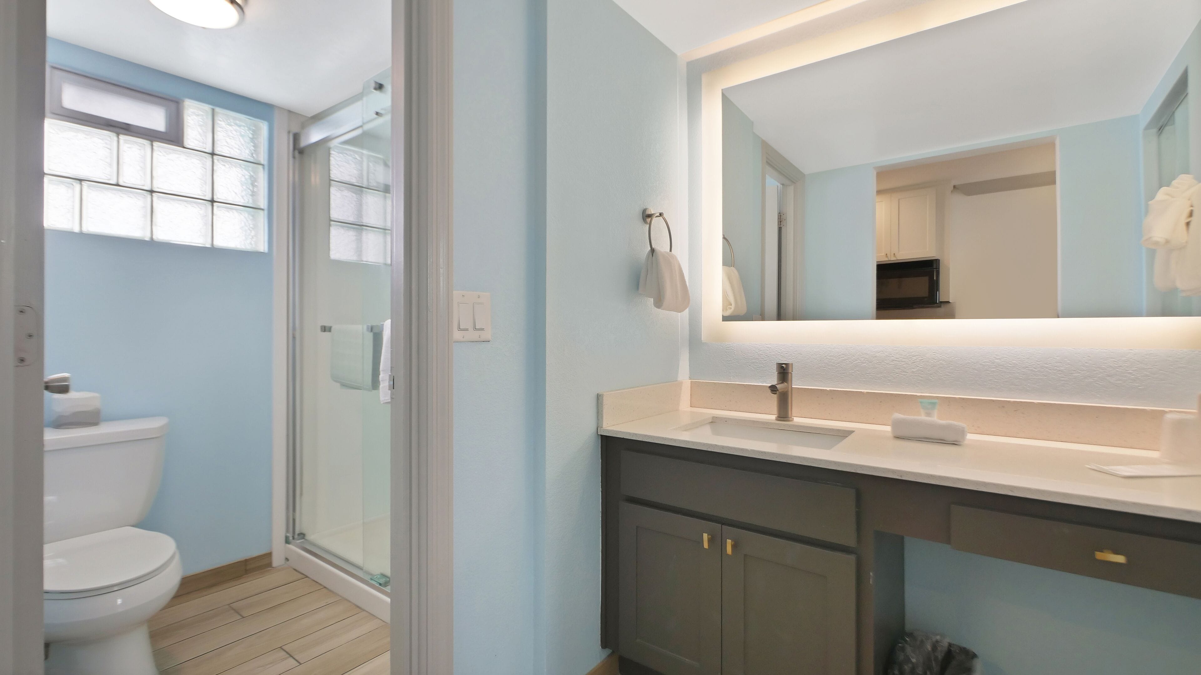 Une salle de bain moderne avec une douche à parois de verre, des toilettes blanches, un lavabo avec un miroir et un porte-serviettes.