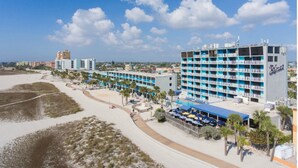 A beachfront hotel with multiple floors, a pool, and a beach area with umbrellas. - Bilmar Beach Resort (Treasure Island)
