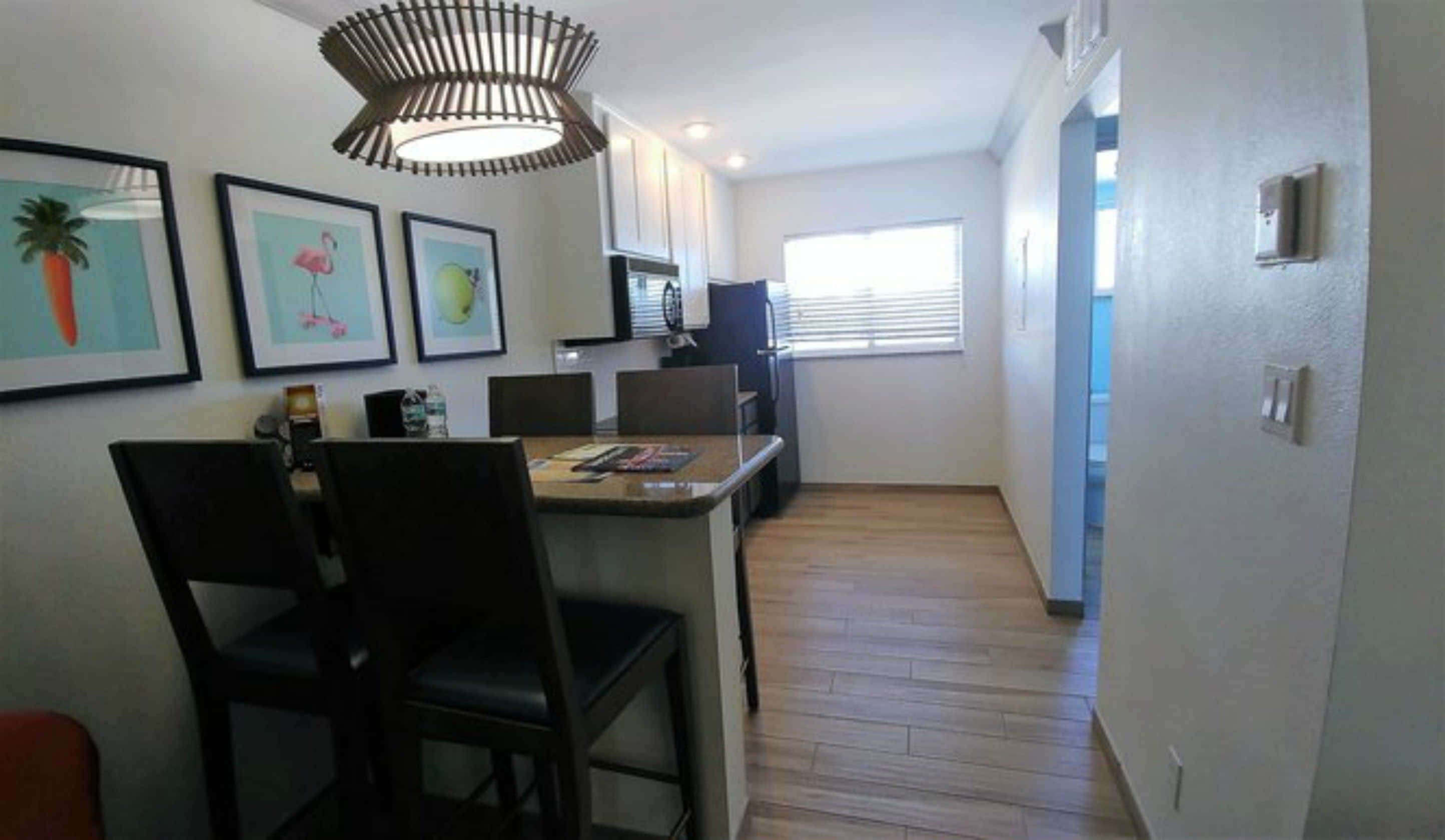Una cocina moderna con comedor, que incluye una isla central, sillas y cuadros en la pared.