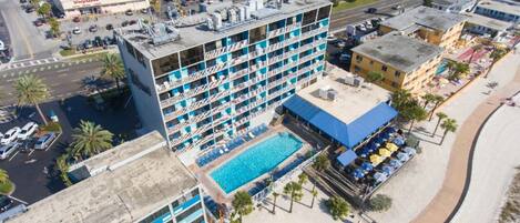 Un hotel de varios pisos con piscina en la azotea y ubicación frente al mar.