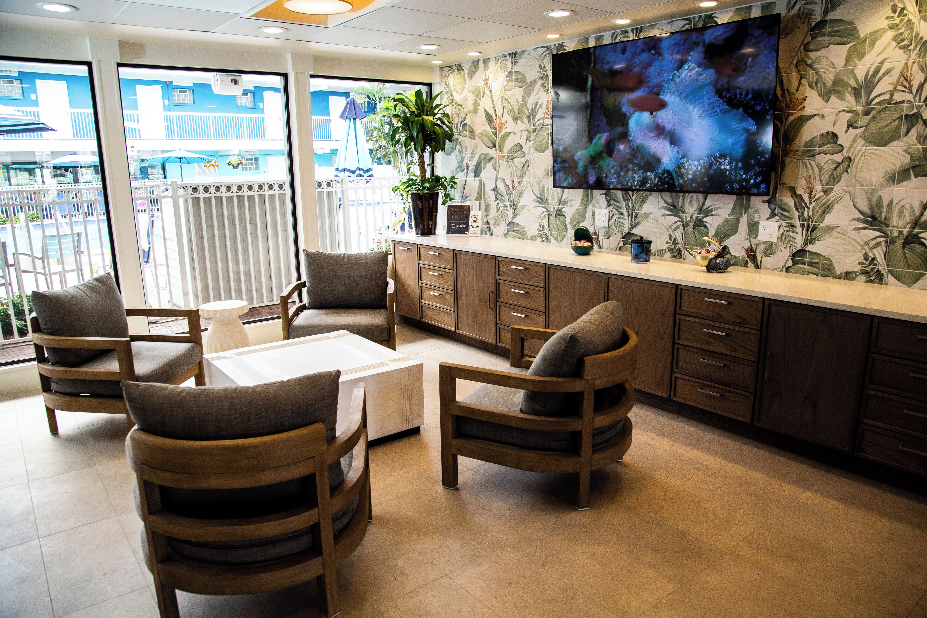 A reception area with a TV, wooden furniture, a plant, and a view of the outside.