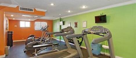 Un gimnasio con cintas de correr y equipo de ejercicio, paredes naranja y una pared de acento verde.