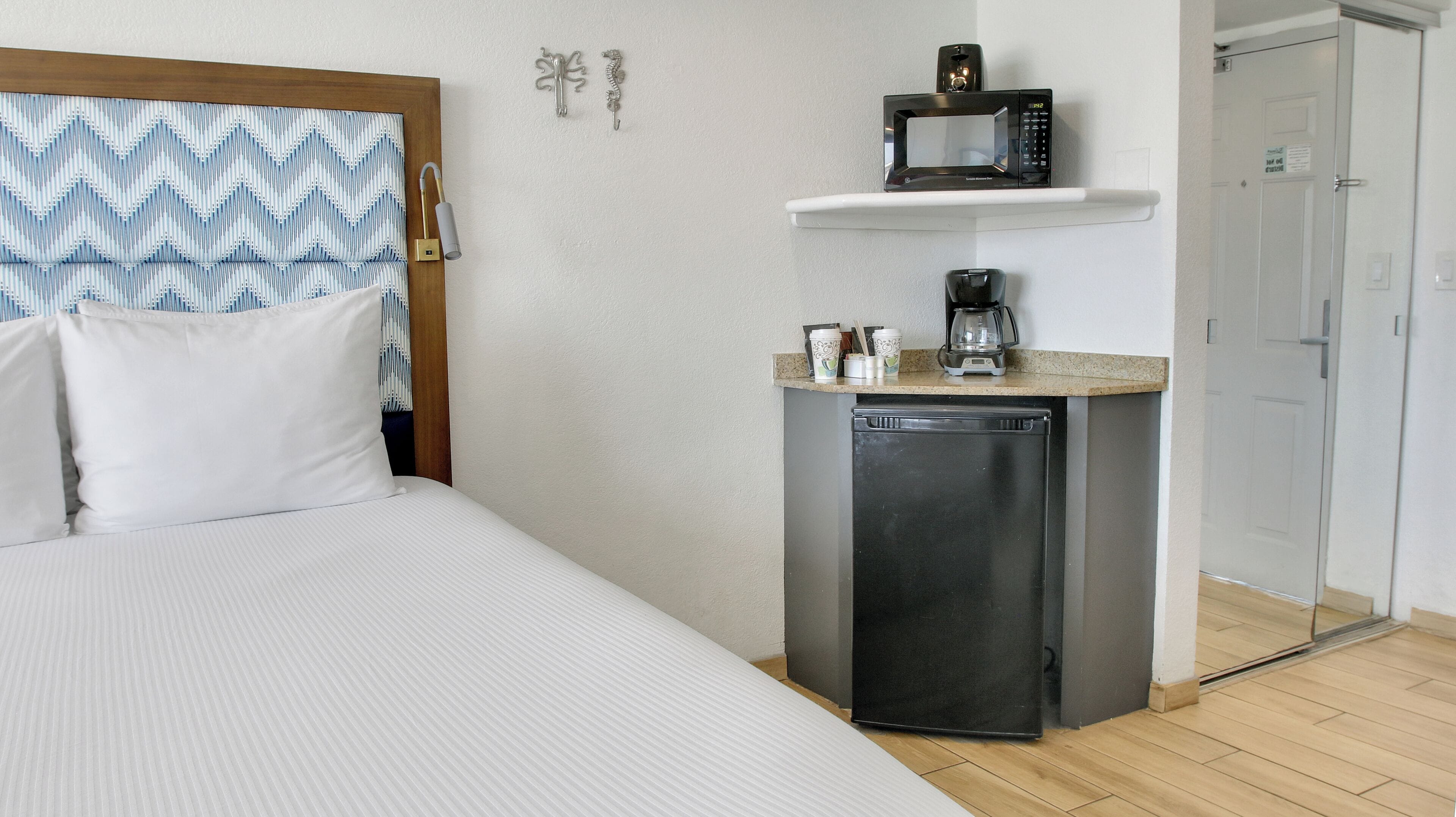 Hotellihuone, jossa on sänky, pieni keittonurkkaus, jossa on mikroaaltouuni, kahvinkeitin ja jääkaappi.