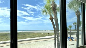 A beach view from a window with palm trees, a sandy path, and beach chairs. - Bilmar Beach Resort (Treasure Island)