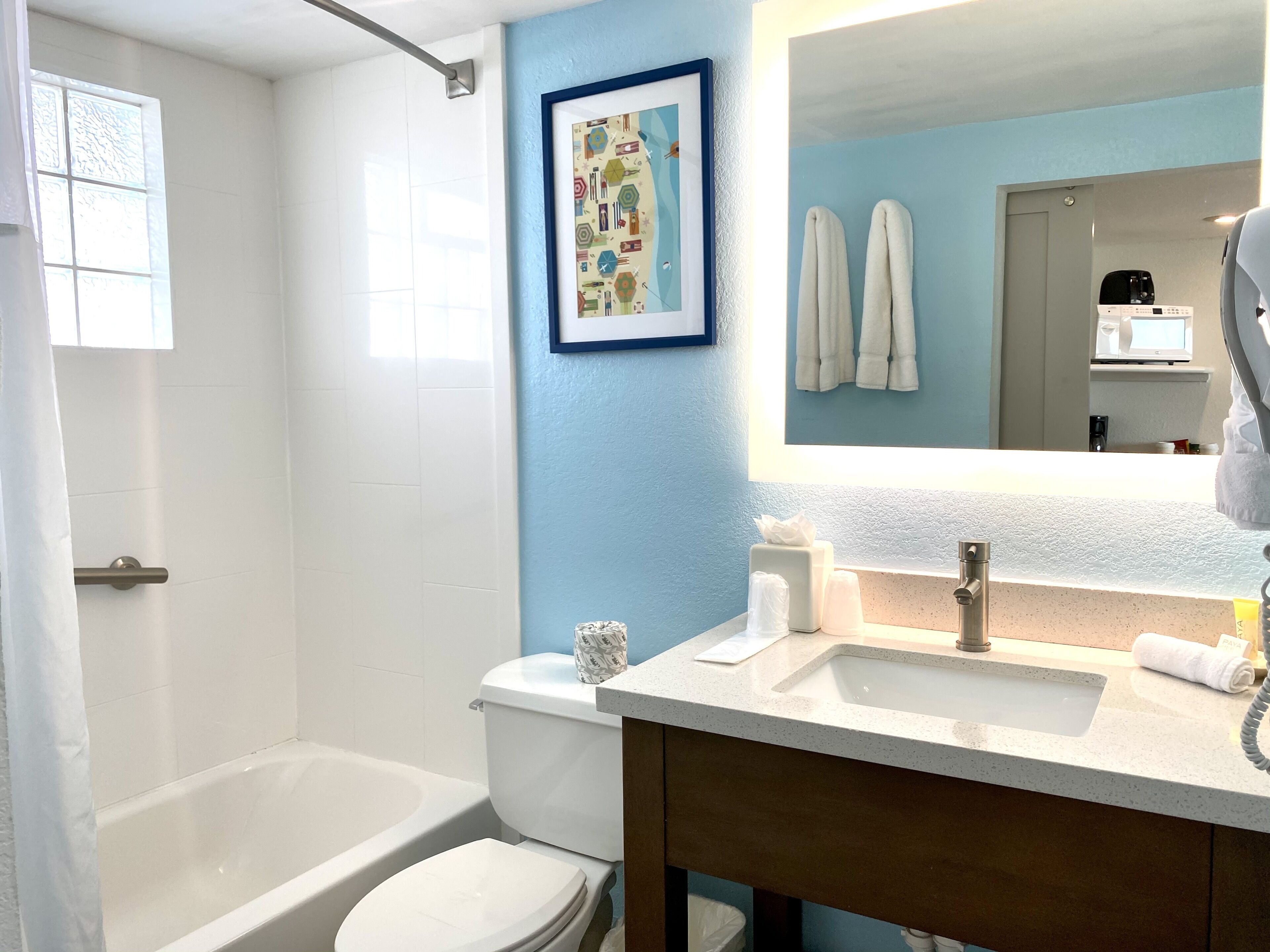 A bathroom with a bathtub, toilet, sink, and a large mirror.