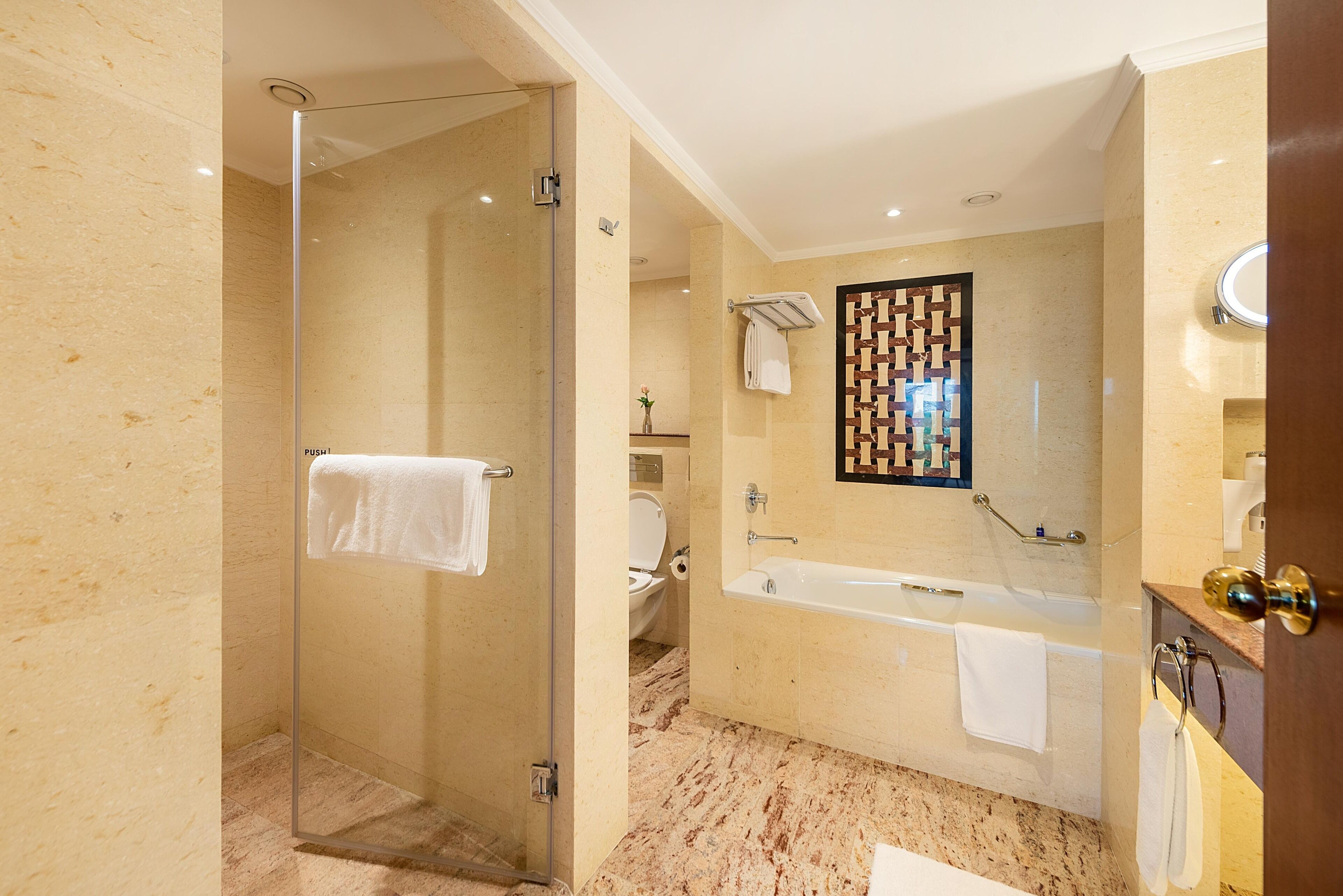 Une salle de bain moderne avec une douche à l’italienne, une baignoire et un grand miroir agrémenté d’un cadre décoratif.