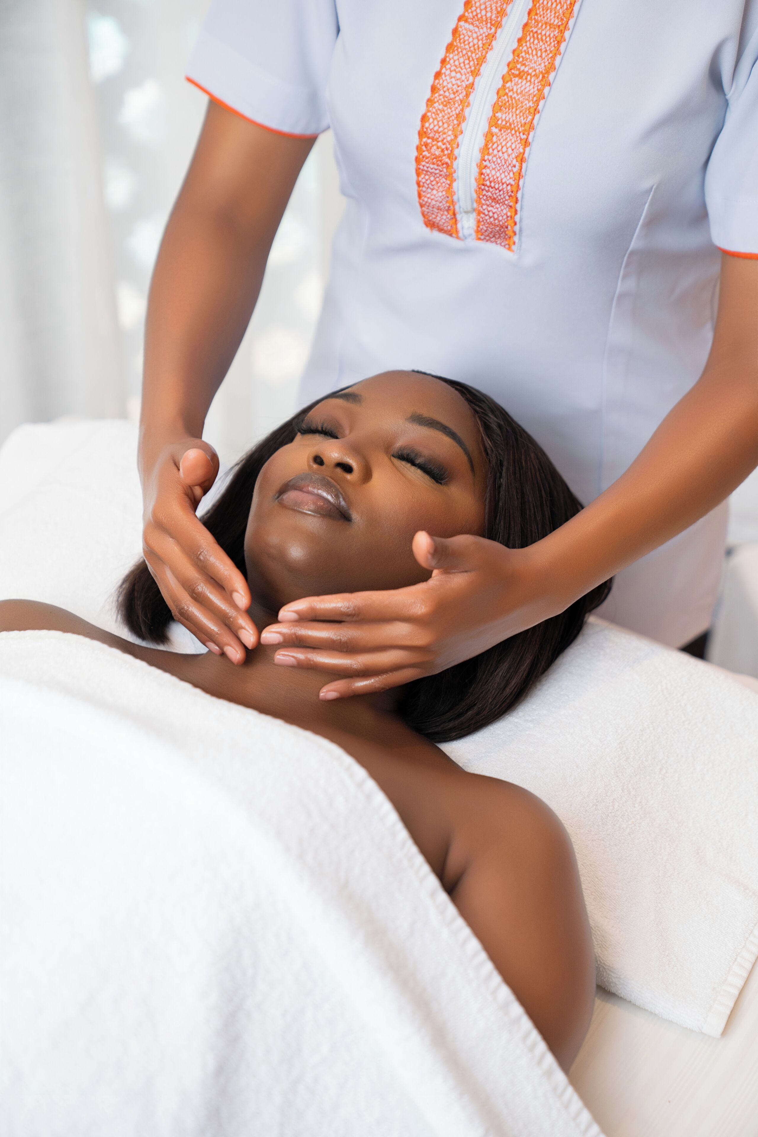 A person receiving a massage in a room with a white bed and a white towel.
