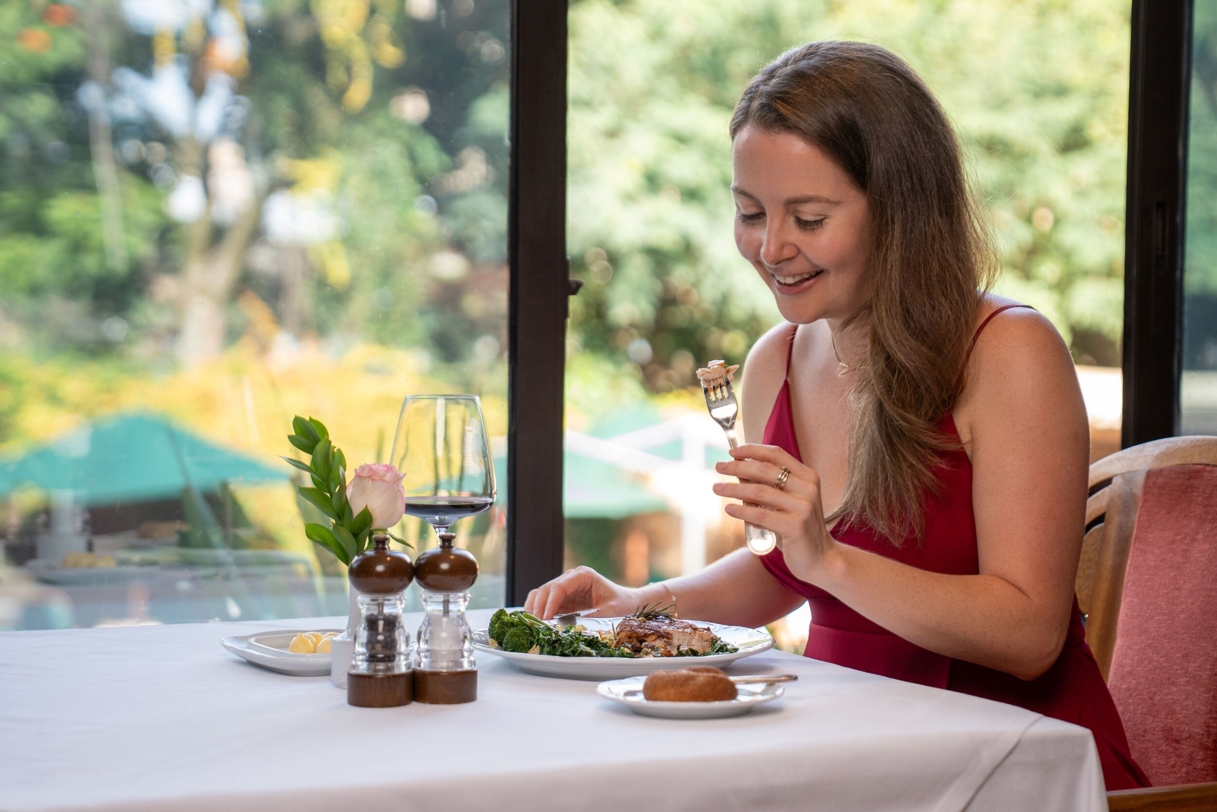 A dining table with plates of food, a wine glass, and a salt and pepper shaker.