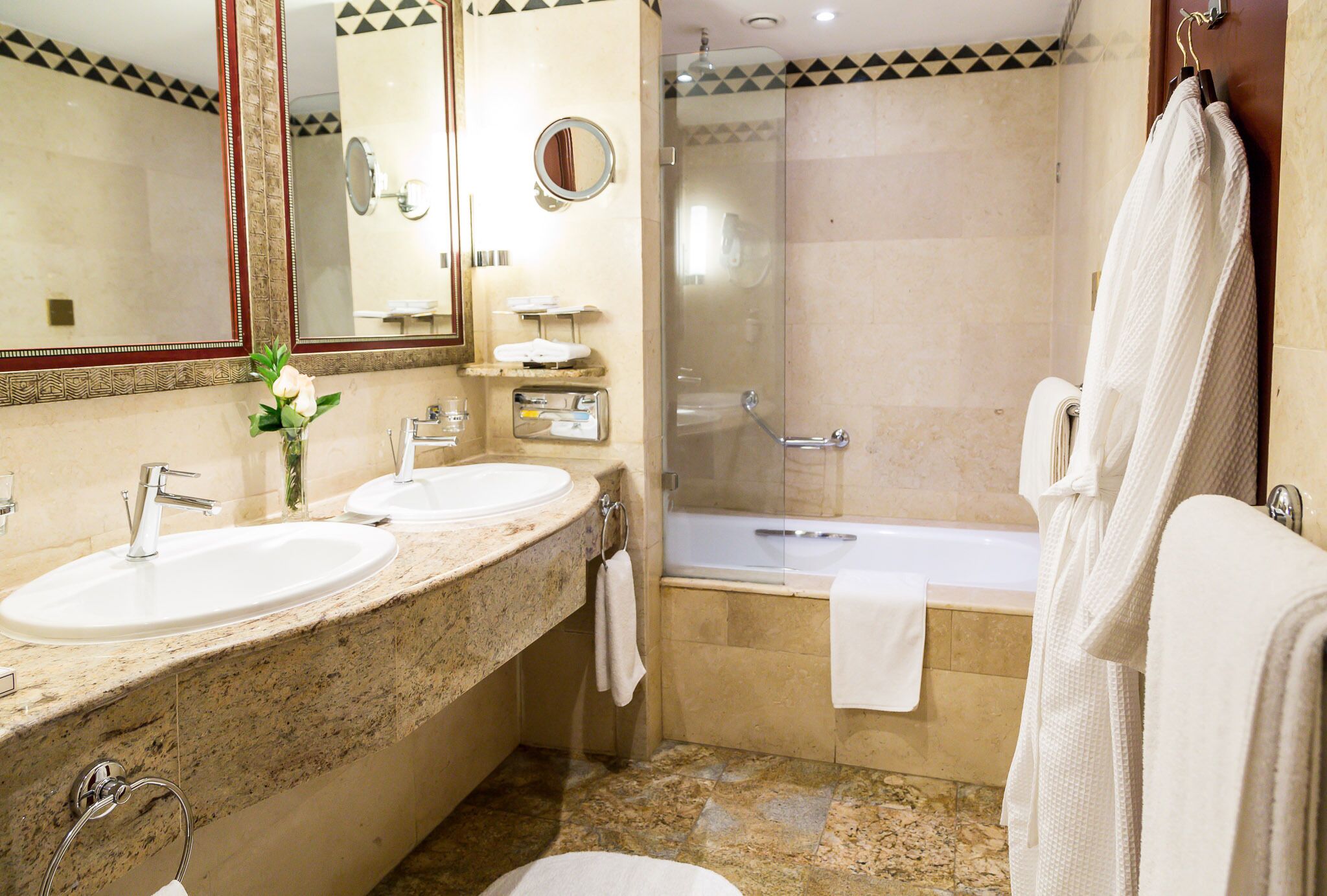 A bathroom with two sinks, a mirror, a shower, and a bathtub.