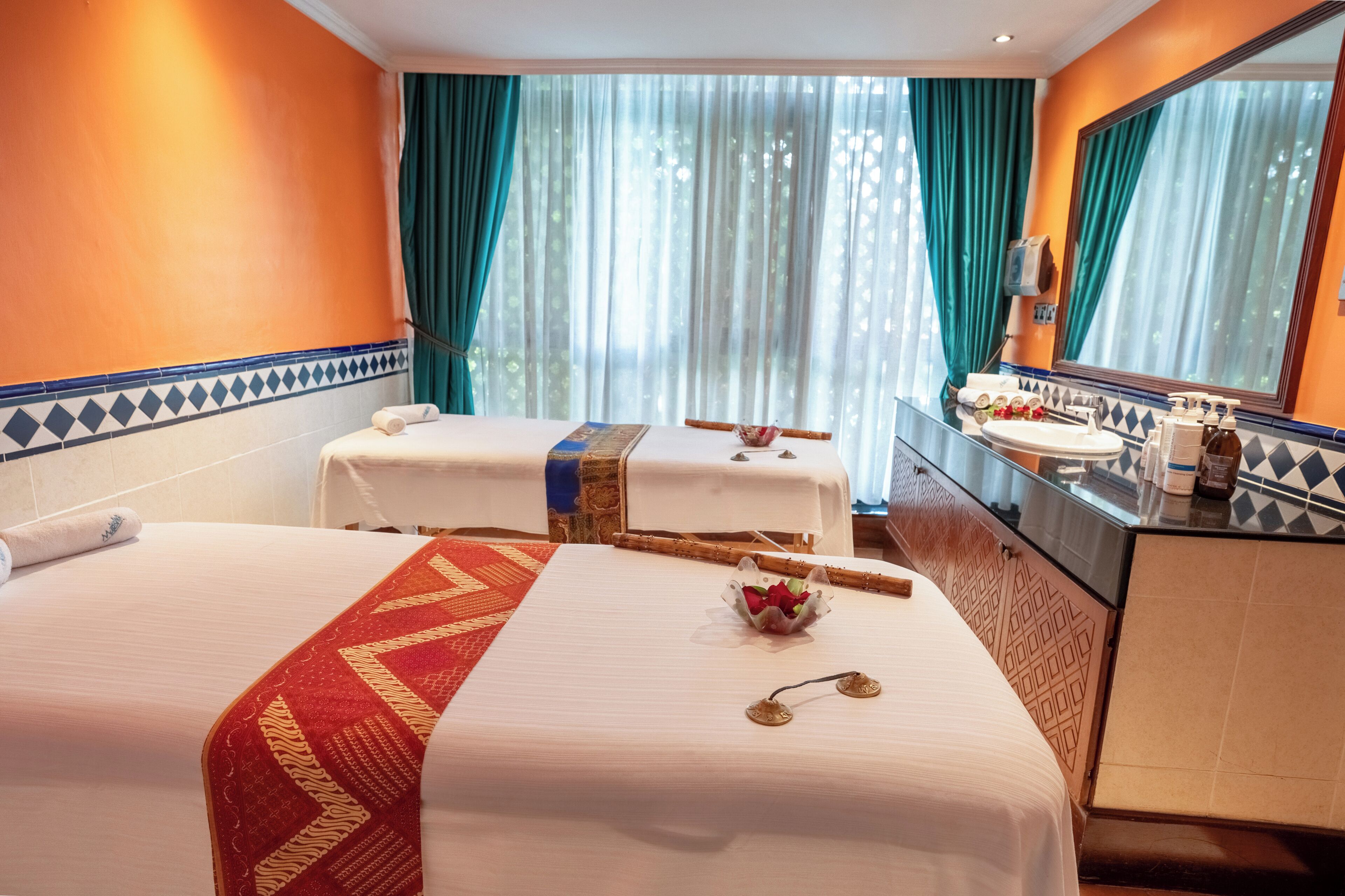 A hotel room with two beds, a bathroom, and a large window with curtains.
