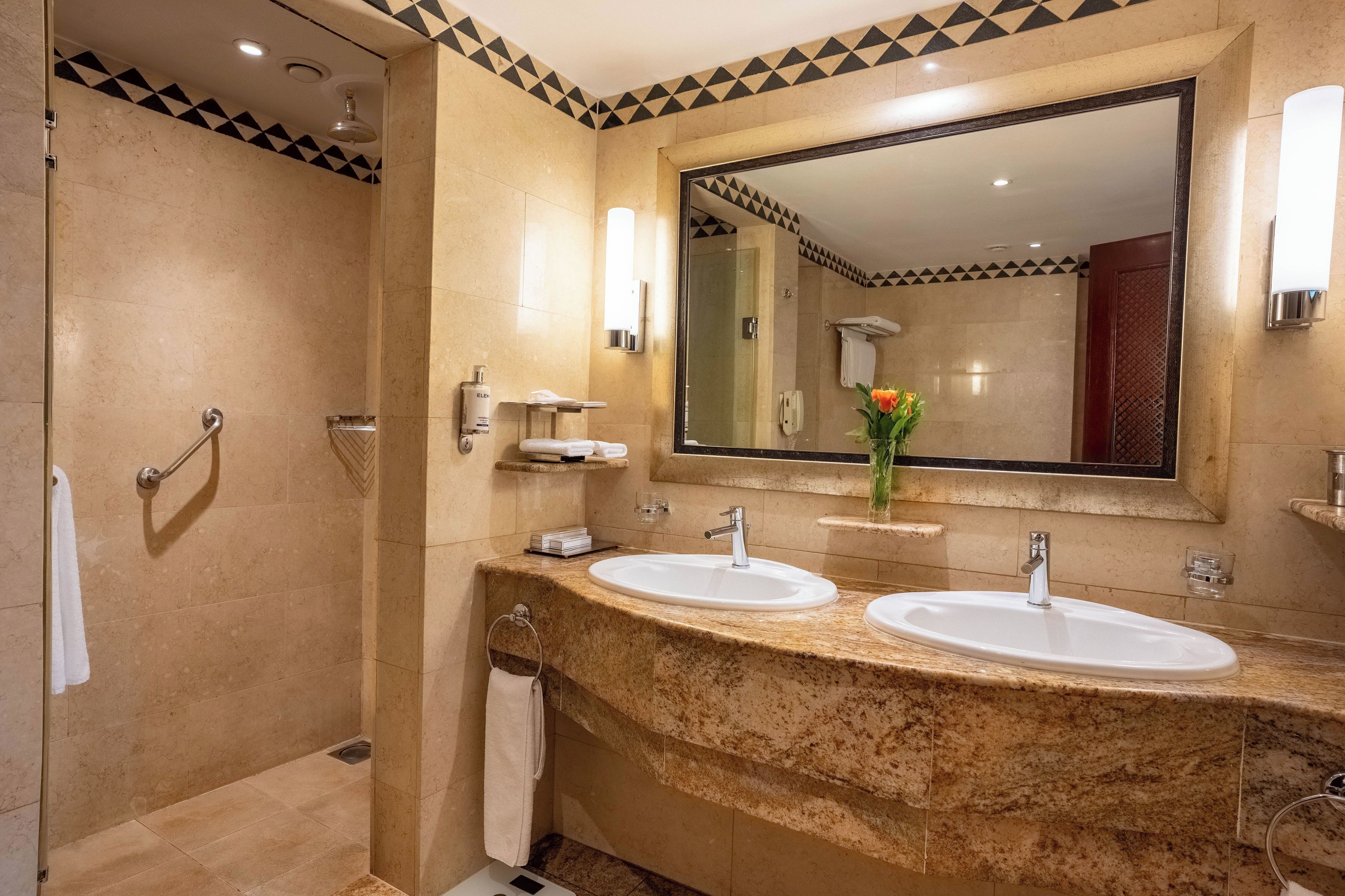 A bathroom with two sinks, a shower, and a large mirror.
