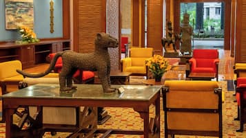 A lobby with a lion statue on a table, red and yellow chairs, and a wooden reception desk.