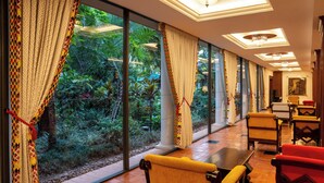 A room with large windows, a dining area with yellow chairs, and a view of greenery outside. - Nairobi Serena Hotel (Nairobi)