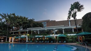 A hotel with a swimming pool, outdoor seating, and a building with multiple floors. - Nairobi Serena Hotel (Nairobi)