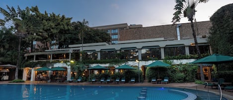Un hotel con piscina, asientos al aire libre y un edificio de varios pisos.