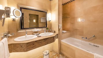 Une salle de bain moderne avec deux lavabos, un grand miroir, une baignoire et des toilettes.