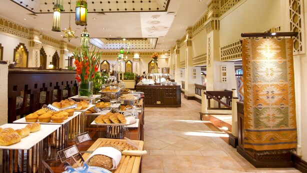A spacious hotel lobby with a high ceiling, ornate chandeliers, and a variety of baked goods displayed on tables. - Nairobi Serena Hotel (Nairobi)