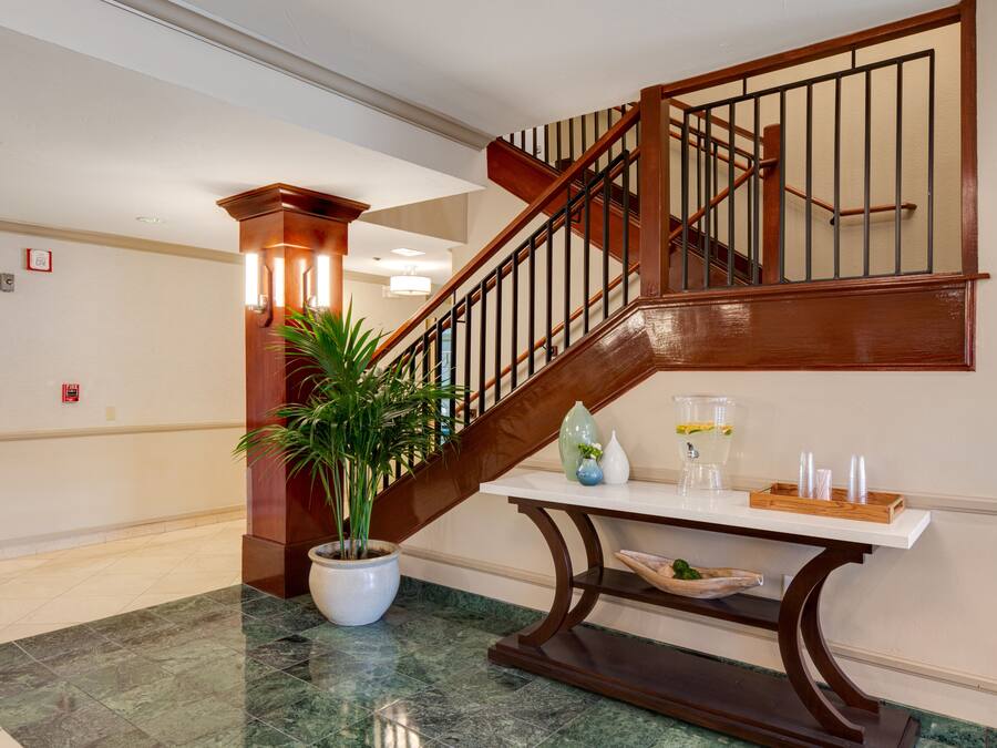 Una escalera con barandillas de madera y piso de mármol.