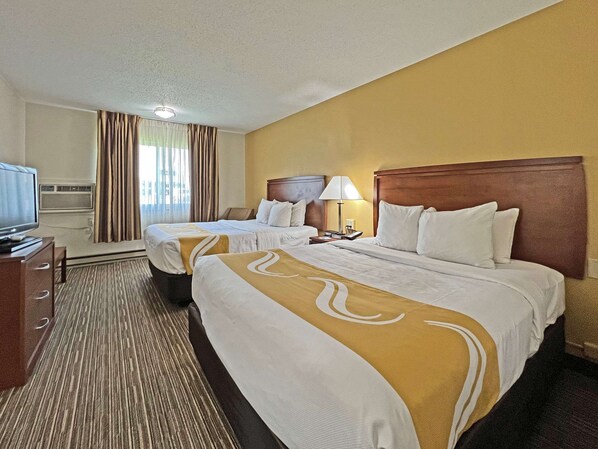 Two single beds with matching headboards, a flat-screen TV, and a desk with a lamp.