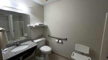 Un baño con lavamanos, inodoro y barras de apoyo.