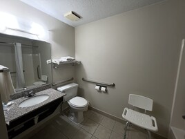 Un baño con lavamanos, inodoro y barras de apoyo.