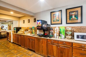 A hotel kitchen with a coffee station, a microwave, and various food items on the counter.