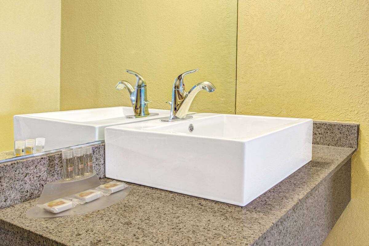 Ein Badezimmer mit zwei weißen Waschbecken, einer Granitplatte und einem Spiegel.