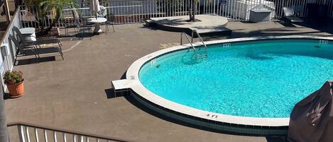 A pool area with a circular pool, lounge chairs, and umbrellas.