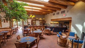 A restaurant with wooden furniture, a bar area, and a large tree providing natural light. - Inn on the Alameda (Santa Fe)