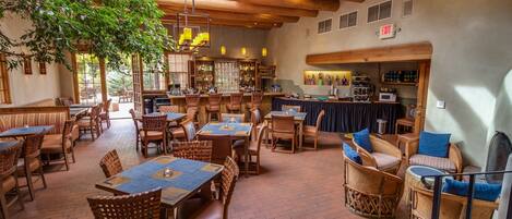 A restaurant with wooden furniture, a bar area, and a large tree providing natural light.
