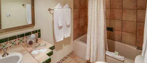 A bathroom with a sink, mirror, shower, and toilet.